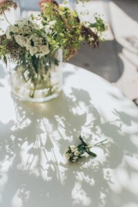 A delicate floral arrangement in a glass vase casting shadows on a sunlit table.